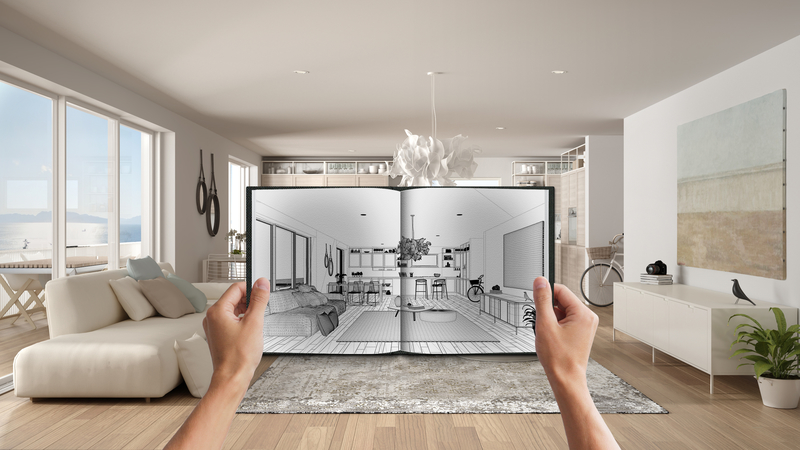 Two hands holding up a sketch of a living room area that looks exactly like the living room area in the back